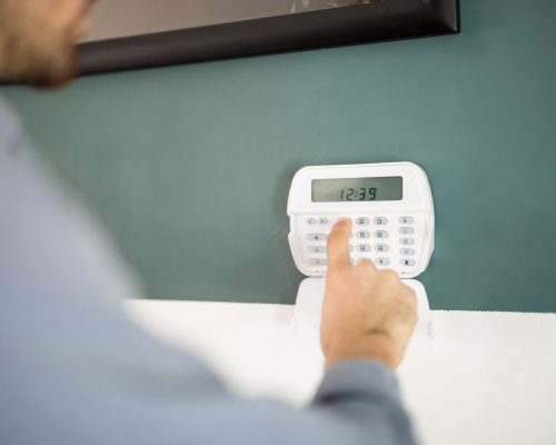 Closeup of the hand of a man using a keypad to arm his home alarm system